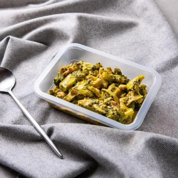 Clear meal container shot of Thai Green Curry, garnished with fresh herbs, set against a grey cloth background for a clean, convenient presentation.
