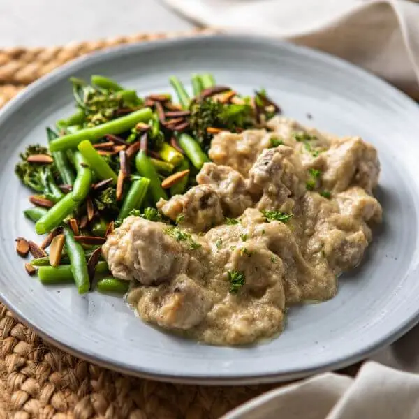 Side angle shot of the Honey Mustard Chicken, showcasing the creamy mustard sauce coating the tender chicken. The rattan placemat and grey marble counter enhance the rustic yet elegant aesthetic.