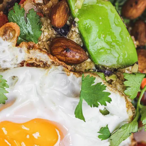 A close-up photograph of our delicious Nasi Goreng, featuring a fried egg, snow peas, cauliflower and almonds.